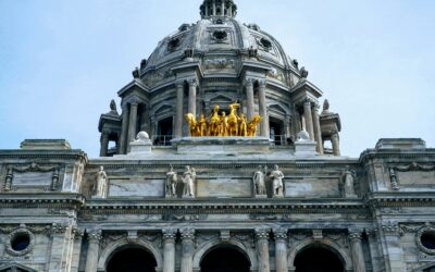Stone domed cathedral facade with ornate columns and a gold sculpture group atop the balcony.